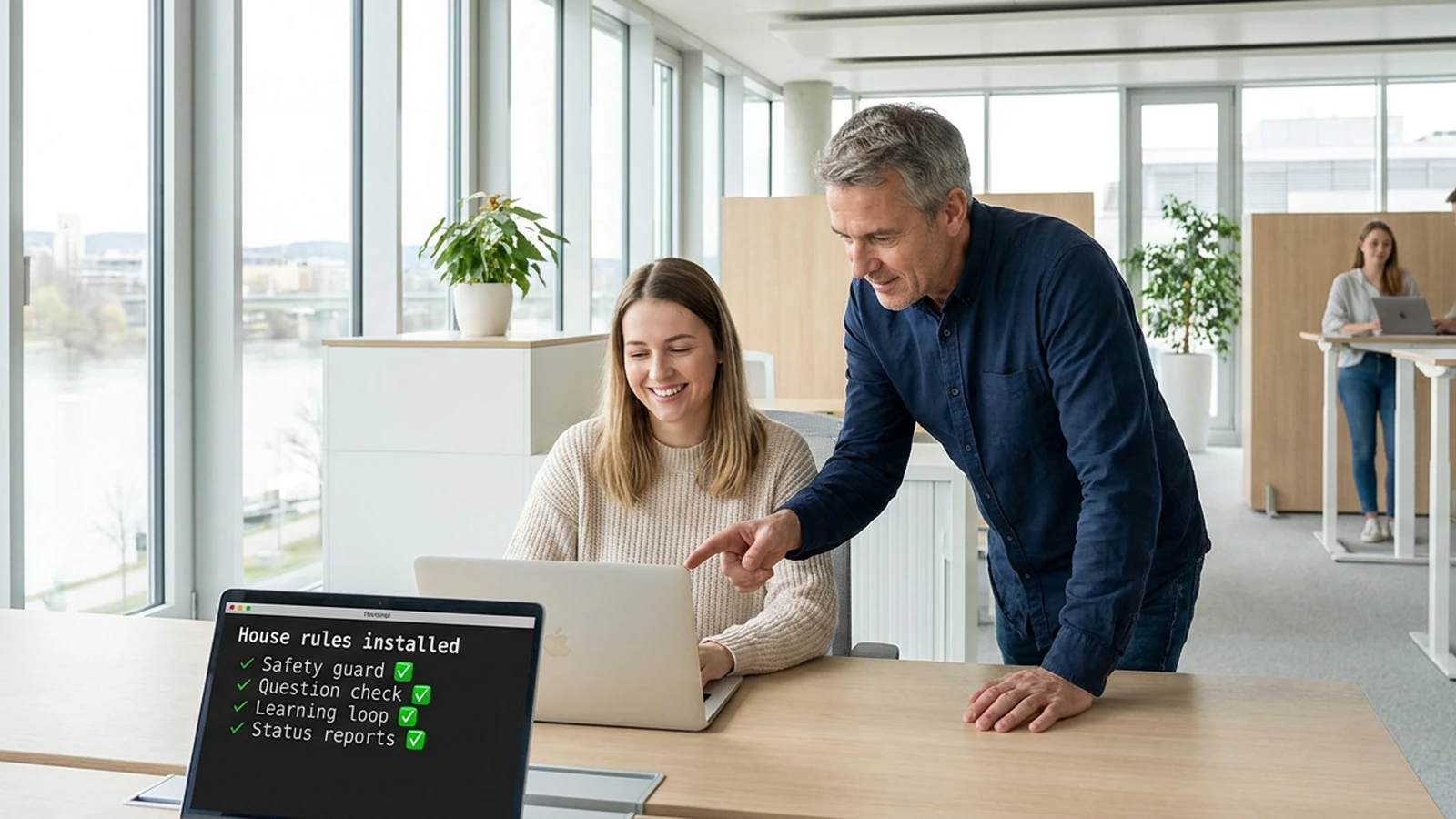 In a bright office on the Danube, an architect points at a colleague's screen, which shows a list headed House rules installed with Safety guard, Question check, Learning loop and Status reports, each with a green checkmark